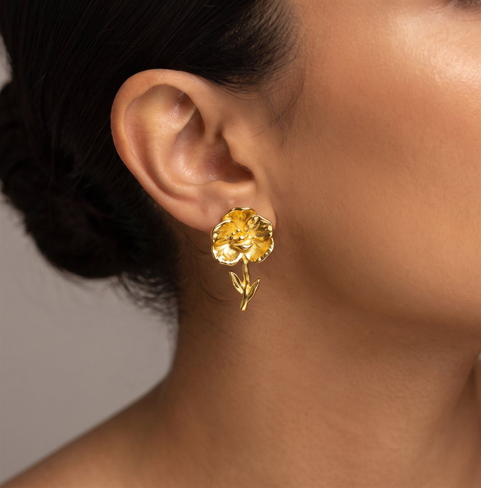 Gold flower stud earring on the ear, worn