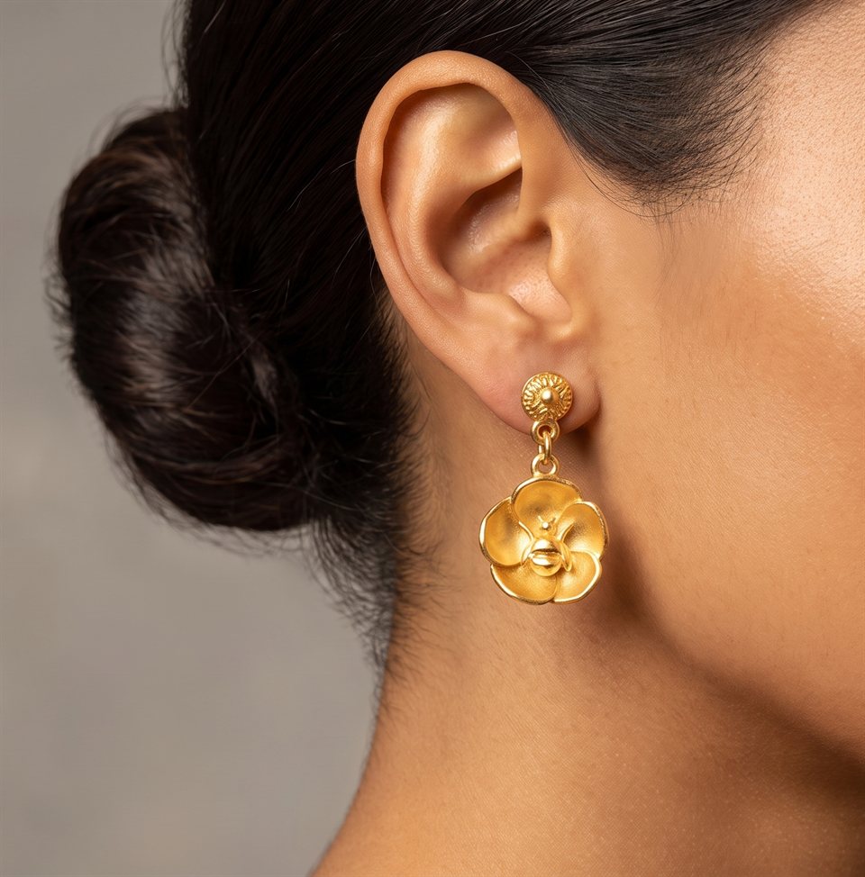 Gold flower pendant on a long twisted chain earring, worn
