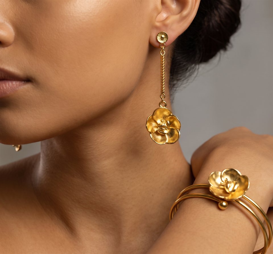 Model wearing a gold flower drop earring with a matching flower bangle on the wrist