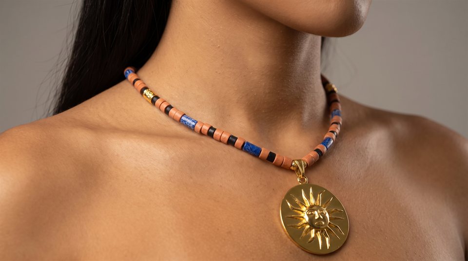 Model wearing a terracotta, black and blue beaded necklace with the Muisca sun in gold