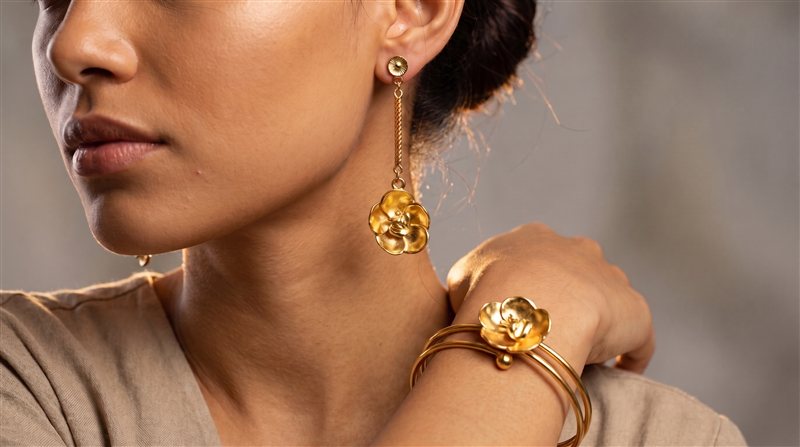 Gold flower drop earring on a twisted chain and matching flower bangle, worn