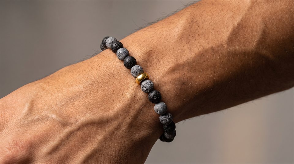 Man wearing a black lava stone bead bracelet with a gold ring bead