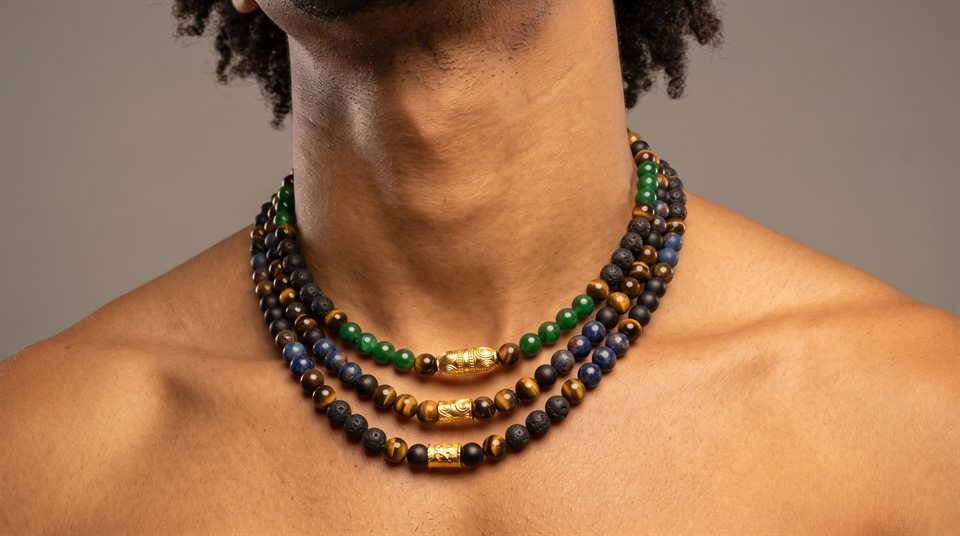 Man wearing a three-strand necklace of tiger's eye, onyx and lava stone with engraved gold beads