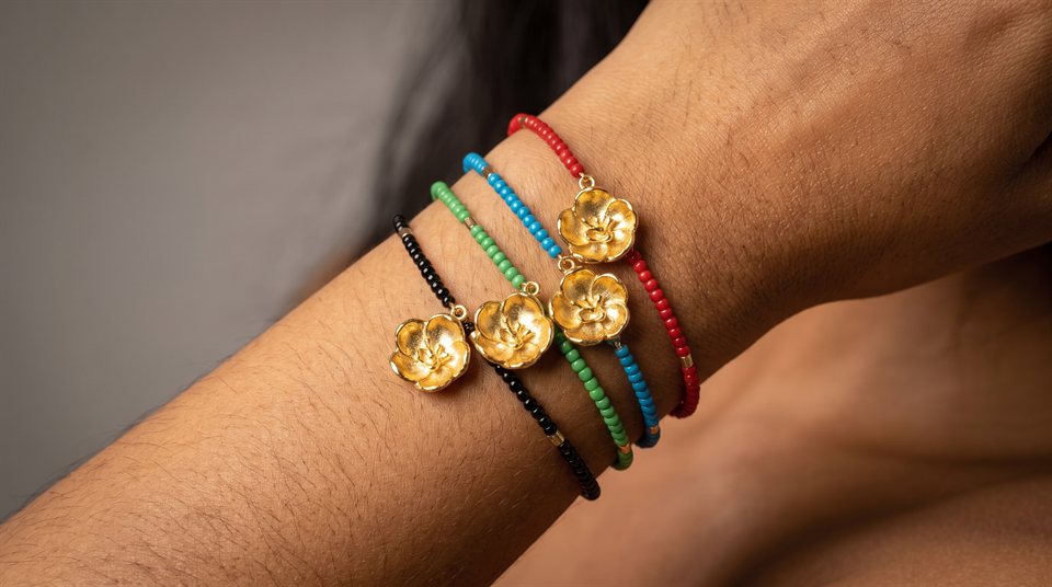 Beaded bracelets in black, green, blue and red with gold Flor del Espíritu Santo charms