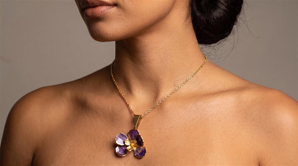 Model wearing a fine gold chain with an amethyst petal flower pendant