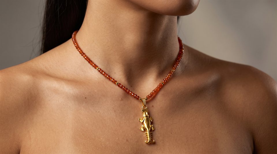 Model wearing carnelian beads with a gold lizard pendant