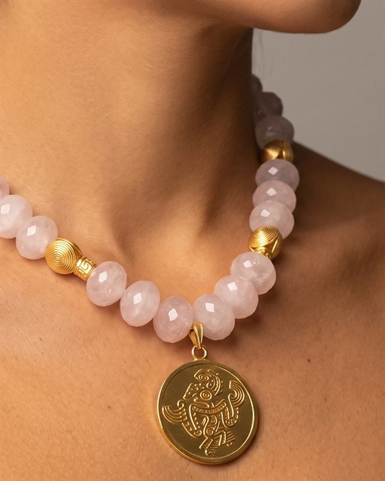 Faceted rose quartz necklace with a gold frog-shaman medallion, worn