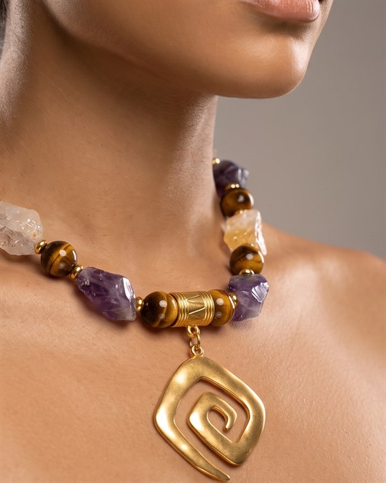 Raw amethyst, quartz and tiger's eye necklace with a gold square-spiral pendant, worn