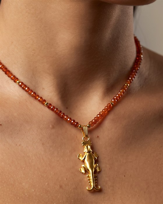 Orange hessonite garnet necklace with a gold lizard pendant, worn
