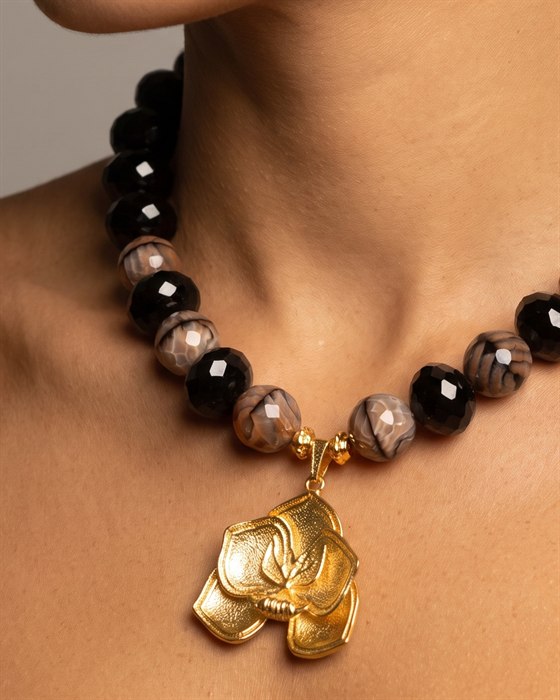 Faceted black onyx necklace with a gold Holy Spirit orchid pendant, worn