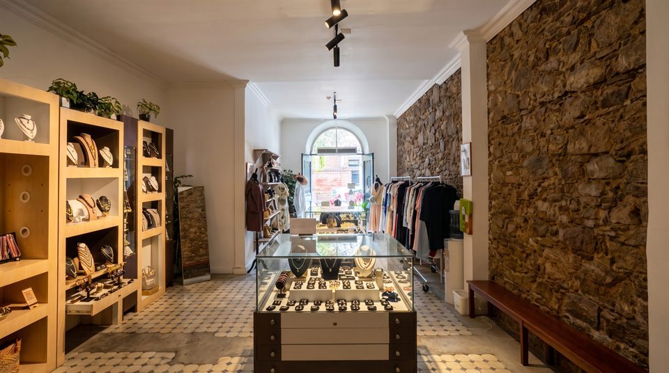 Inside the boutique: jewelry displays, wooden shelves and a colonial stone wall